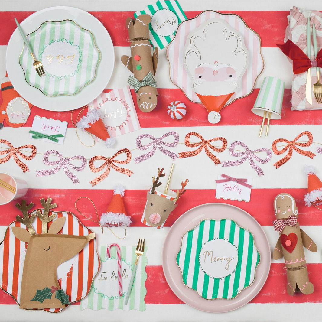 Christmas-themed table setting with decorative plates, cutlery, and gingerbread men on a red and white checkered tablecloth.