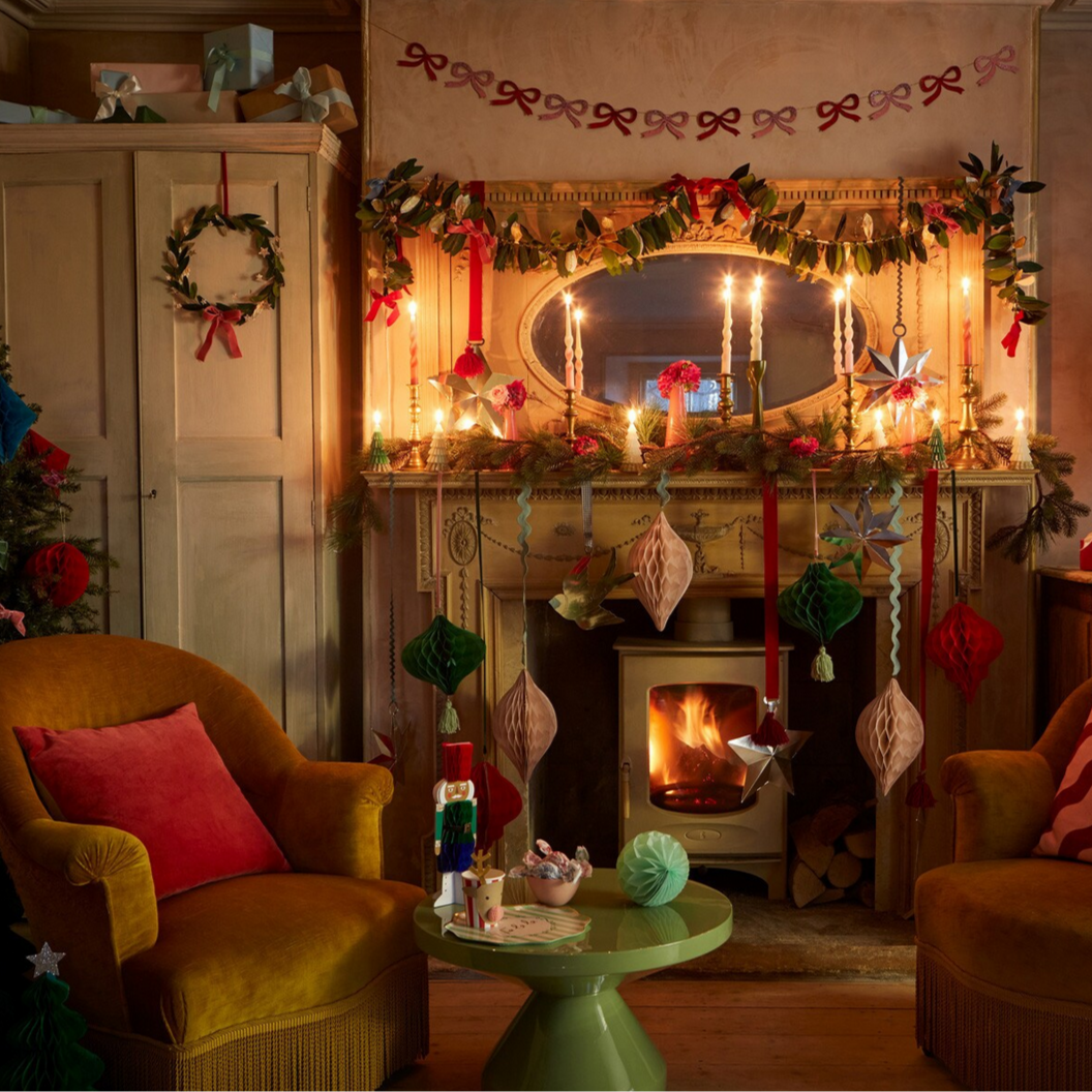 Cozy living room with Christmas decorations, including a fireplace, chairs, and festive items.