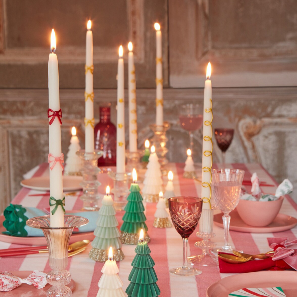 Decorative candles and tableware on a festive table setting with a red and white checkered tablecloth.