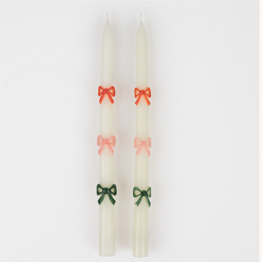 Three white candles with colorful bows on a white background