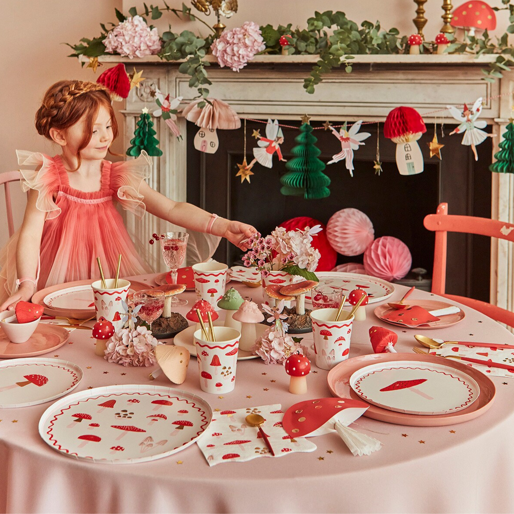 Young girl in a fairy costume at a decorated table with fairy-themed tableware.