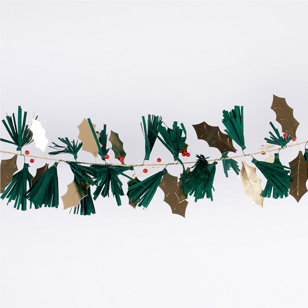 Decorative garland with green leaves, gold holly leaves, and red berries on a white background