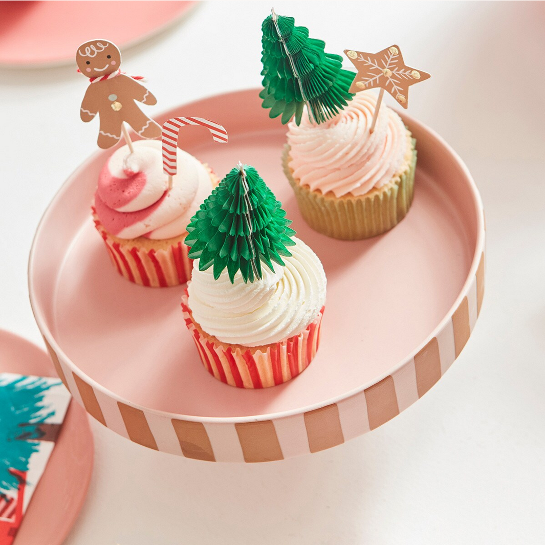 Three cupcakes with festive decorations on a pink plate