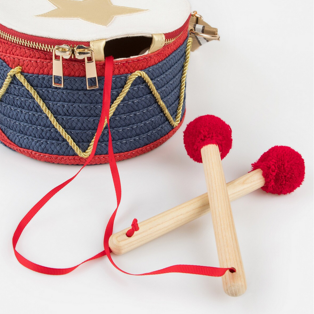 Woven drum with red string and wooden sticks on a white background