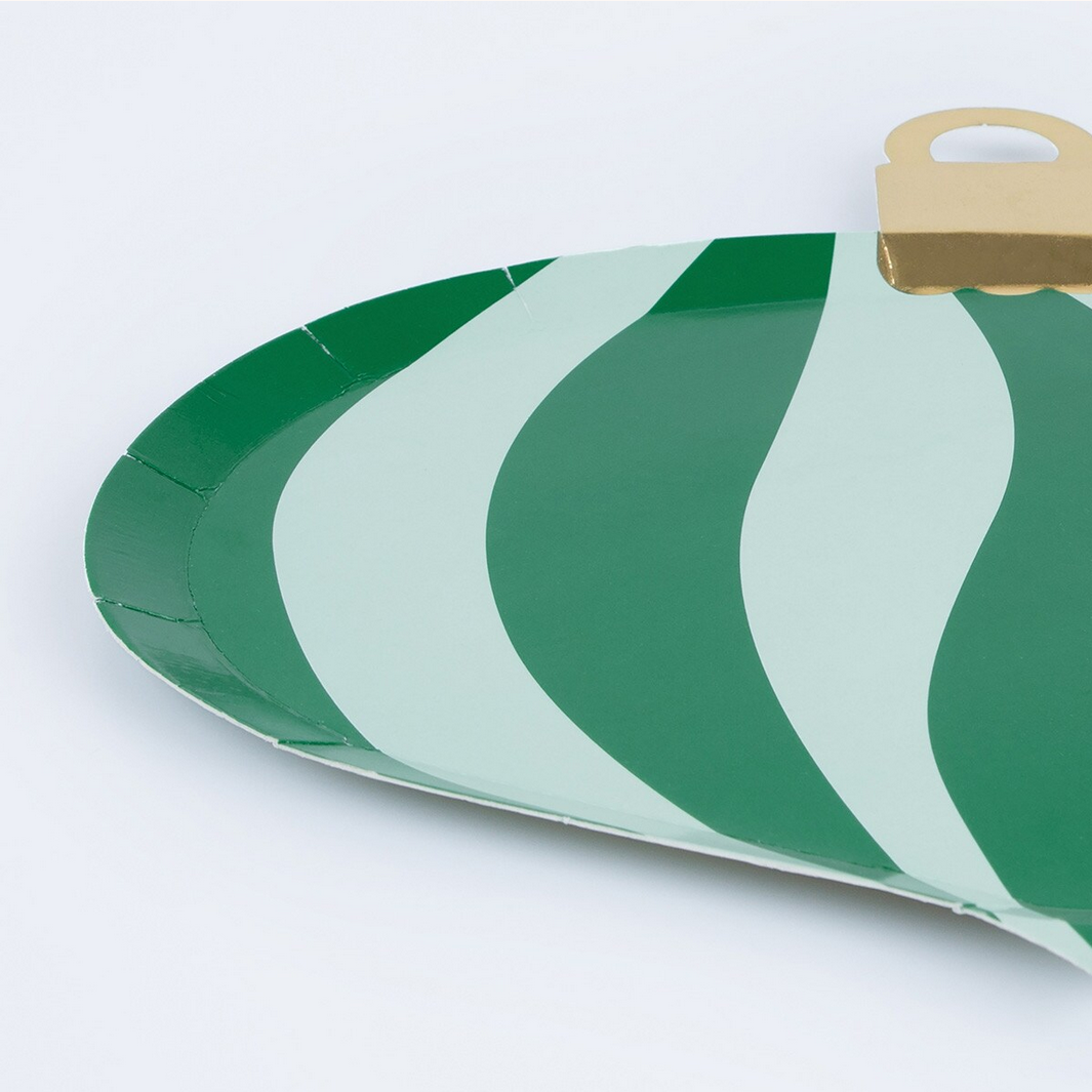 Green and white striped paper plate with a wooden handle on a light gray background