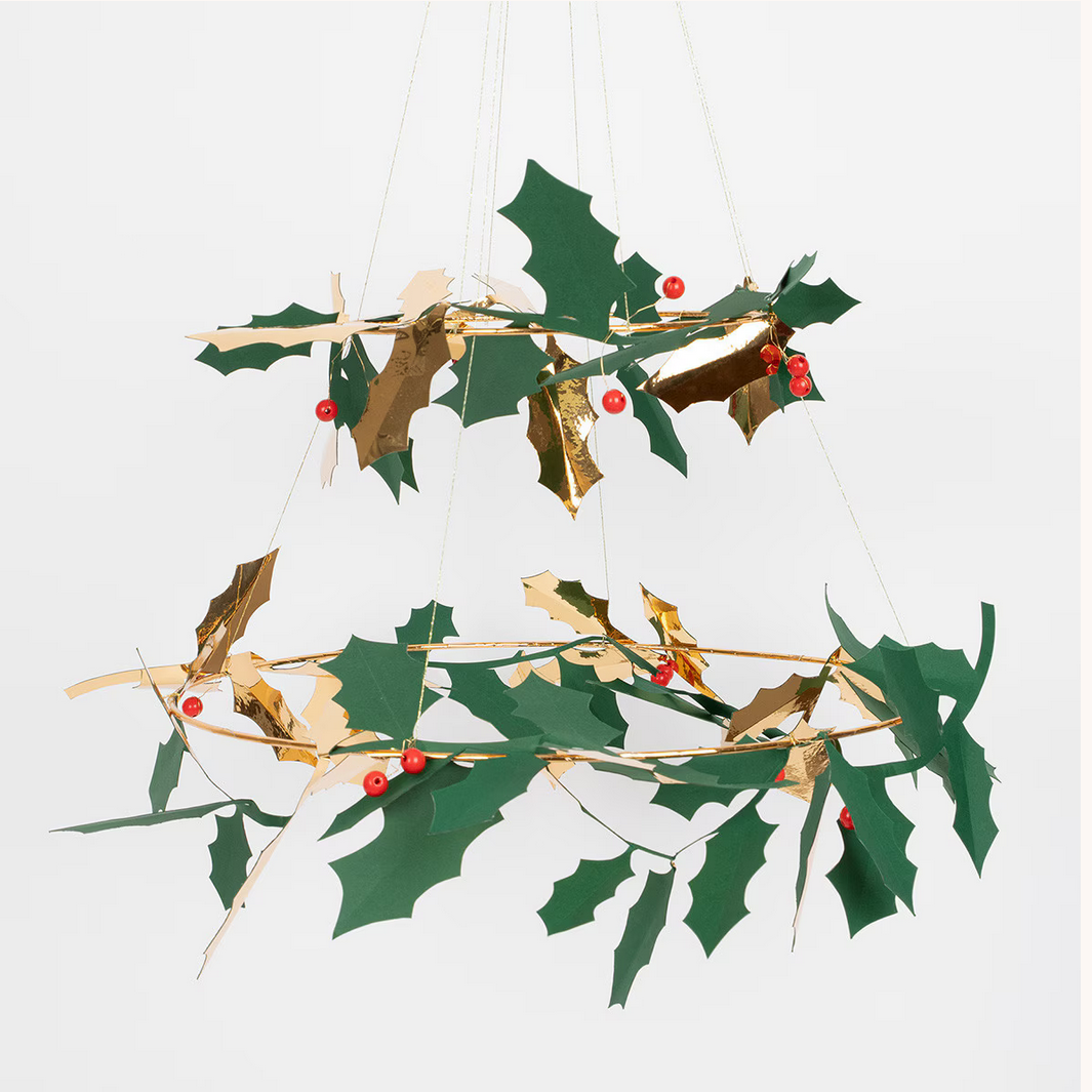 Decorative hanging holly plant with green leaves and red berries on a white background