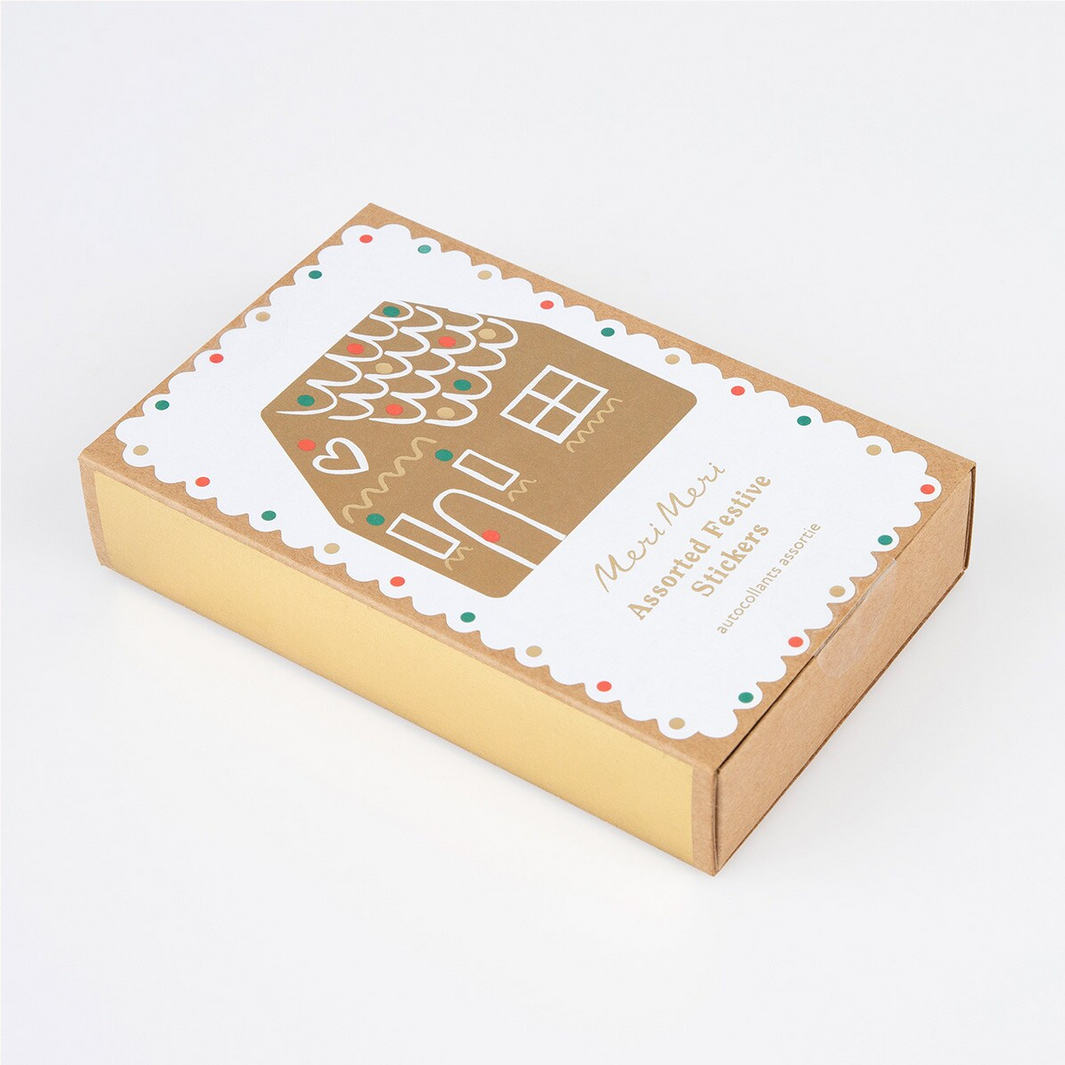 Cardboard box with a decorative label featuring a gingerbread house design on a white background