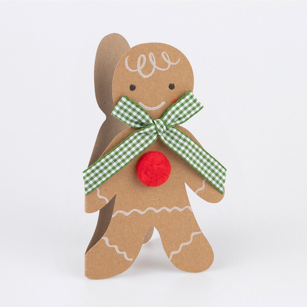 Decorative gingerbread man ornament with a green bow and red button on a white background
