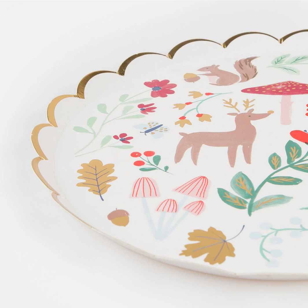 Decorative plate with a forest-themed design featuring deer, mushrooms, and flowers on a white background.