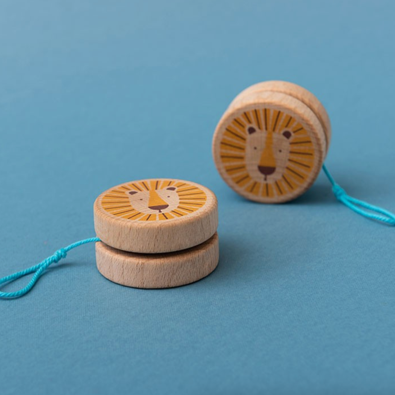 Two wooden lion toys with strings on a blue background