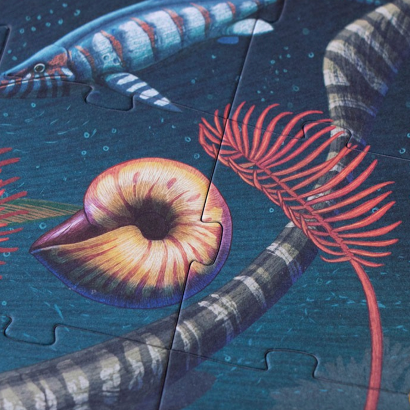 Jigsaw puzzle with a partially completed design of a creature with striped body and red tentacles on a blue background.
