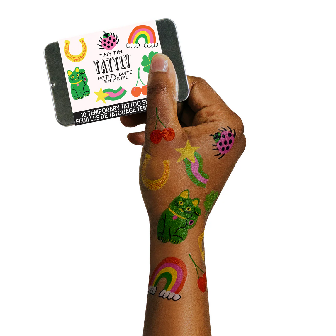 Hand with colorful temporary tattoos held by a card with tattoo designs.