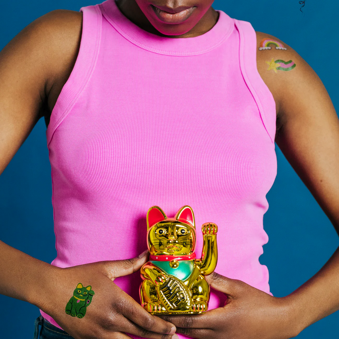 Person holding a gold cat-shaped object against a blue background
