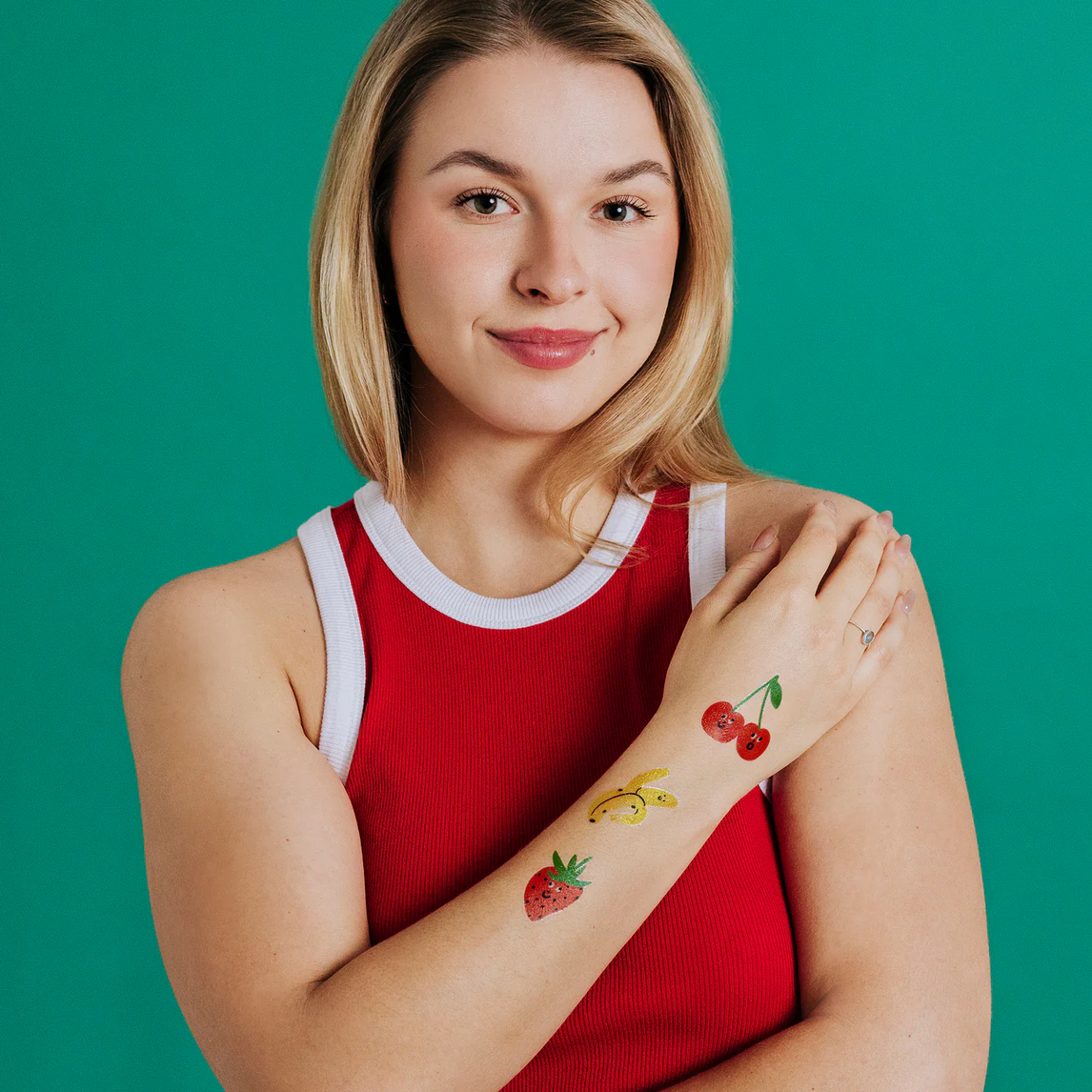 Woman wearing a red sleeveless top with colorful temporary tattoos on a green background