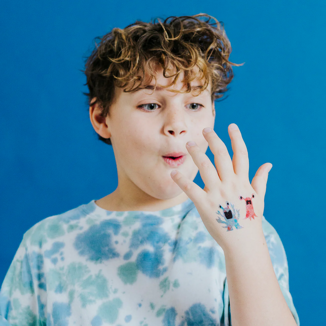 Child with colorful temporary tattoos on a blue background
