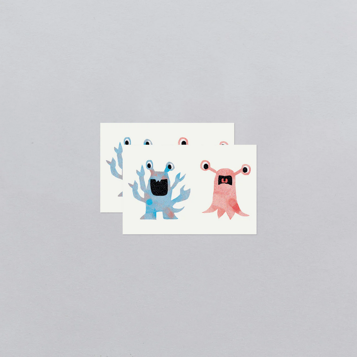 Two cartoon monster stickers on a gray background