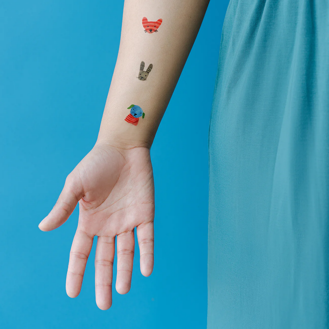 Hand with colorful temporary tattoos against a blue background