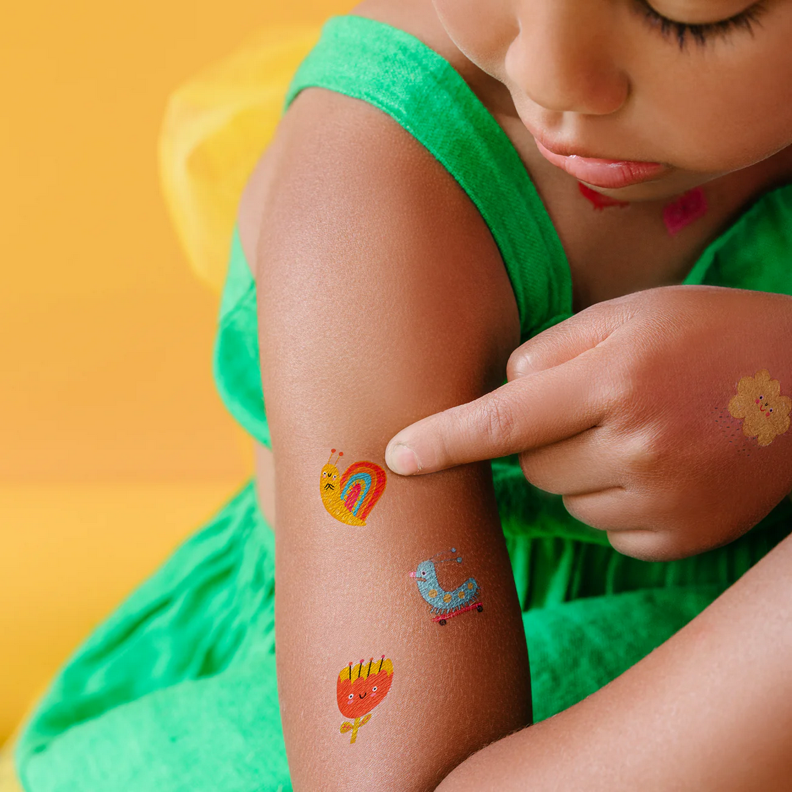 Child wearing colorful temporary tattoos on a yellow background