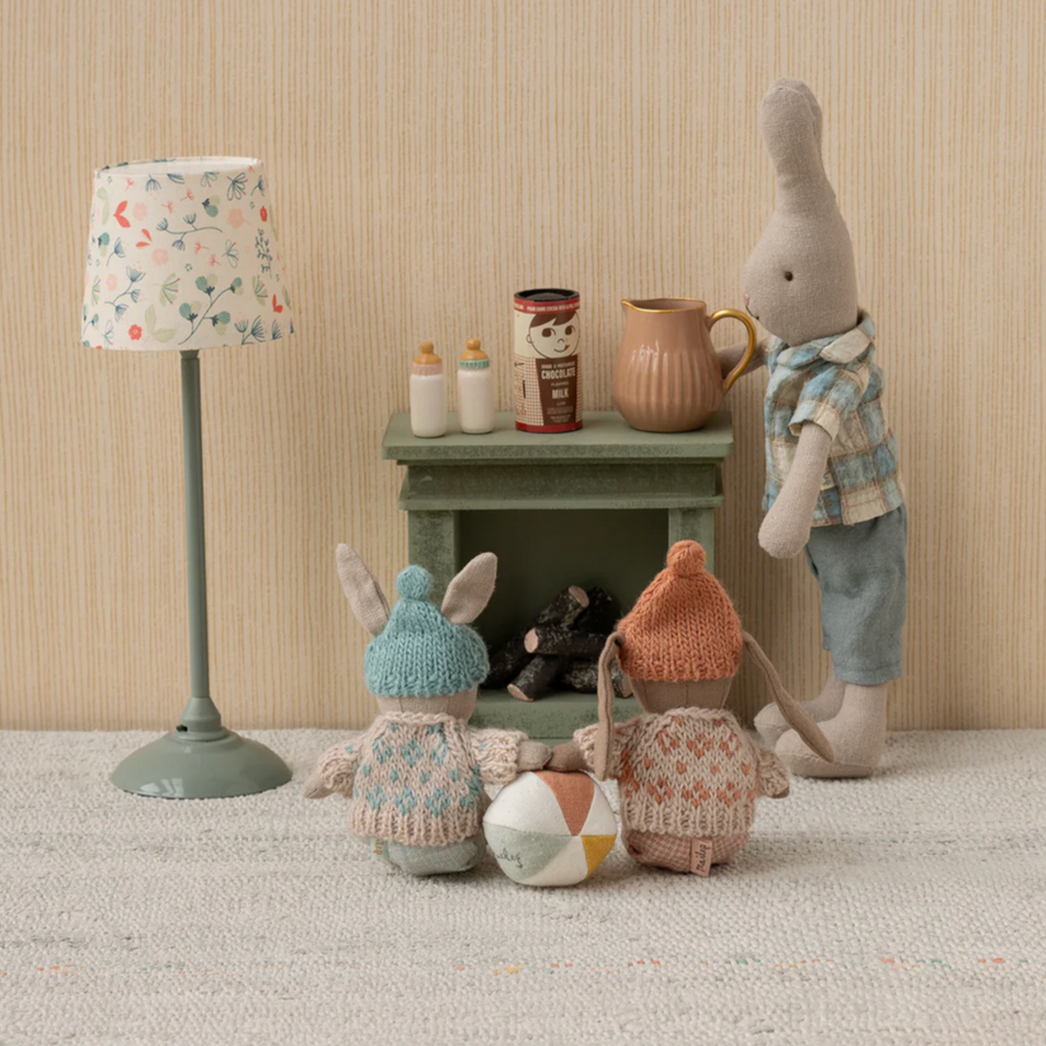 Stuffed animals in a room with a lamp and small table.