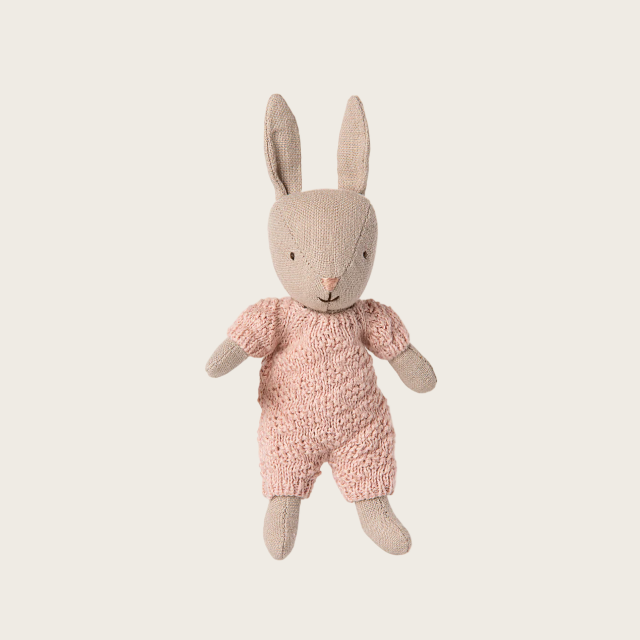 Knitted toy rabbit in a pink outfit on a white background