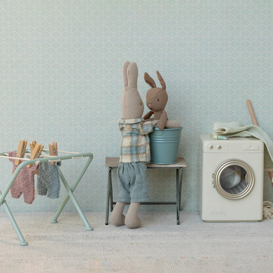 Children's room with toys, washing machine, and dryer against a light blue wall.