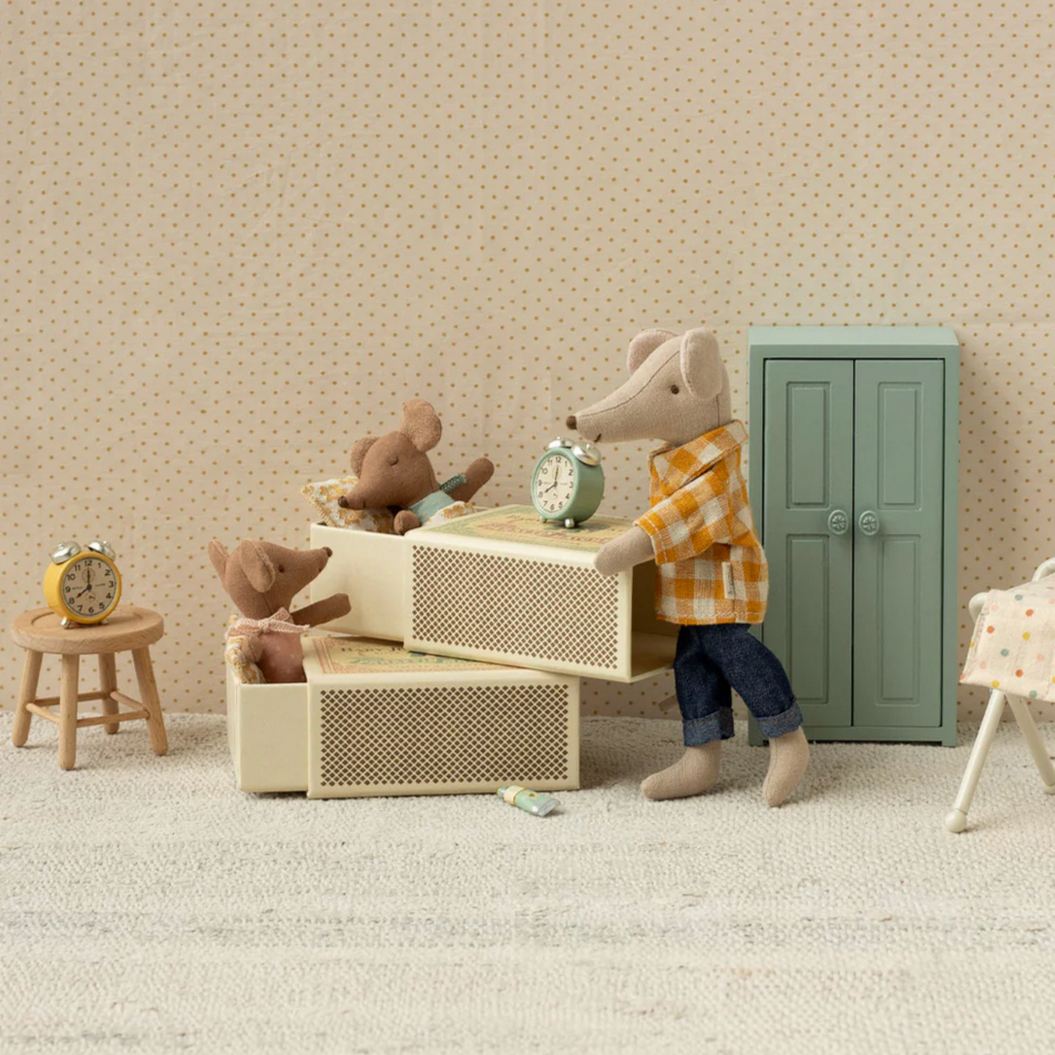 Miniature room setup with a mouse character, furniture, and toys against a beige wall.