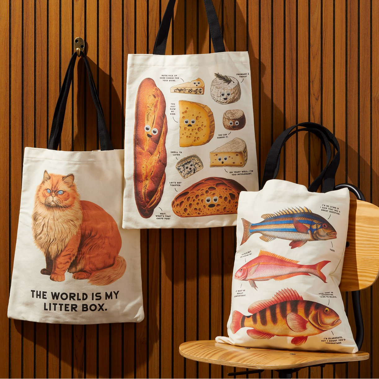 Three tote bags with unique designs on a wooden background