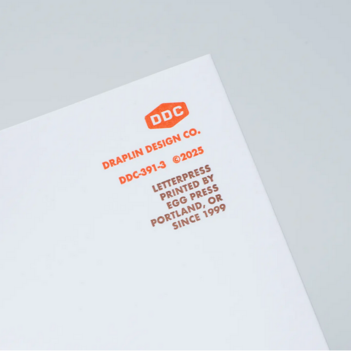 Letterpress printed paper with DDC branding on a light gray background