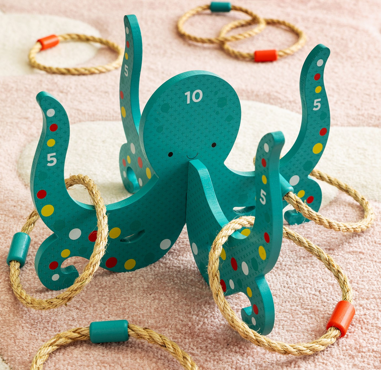 Teal octopus-shaped toy with numbered arms and ropes on a pink background