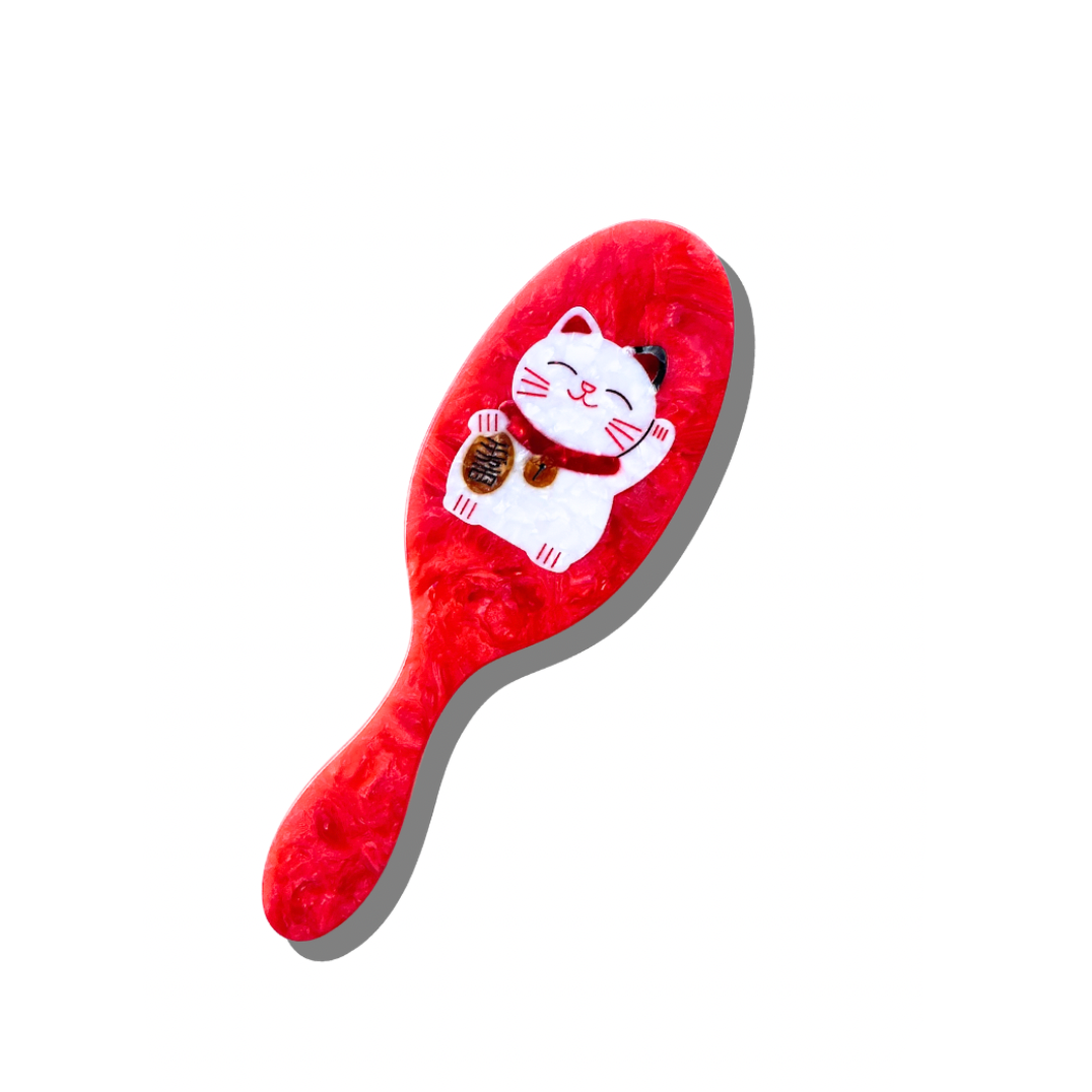 Red hairbrush with a cat design on a white background