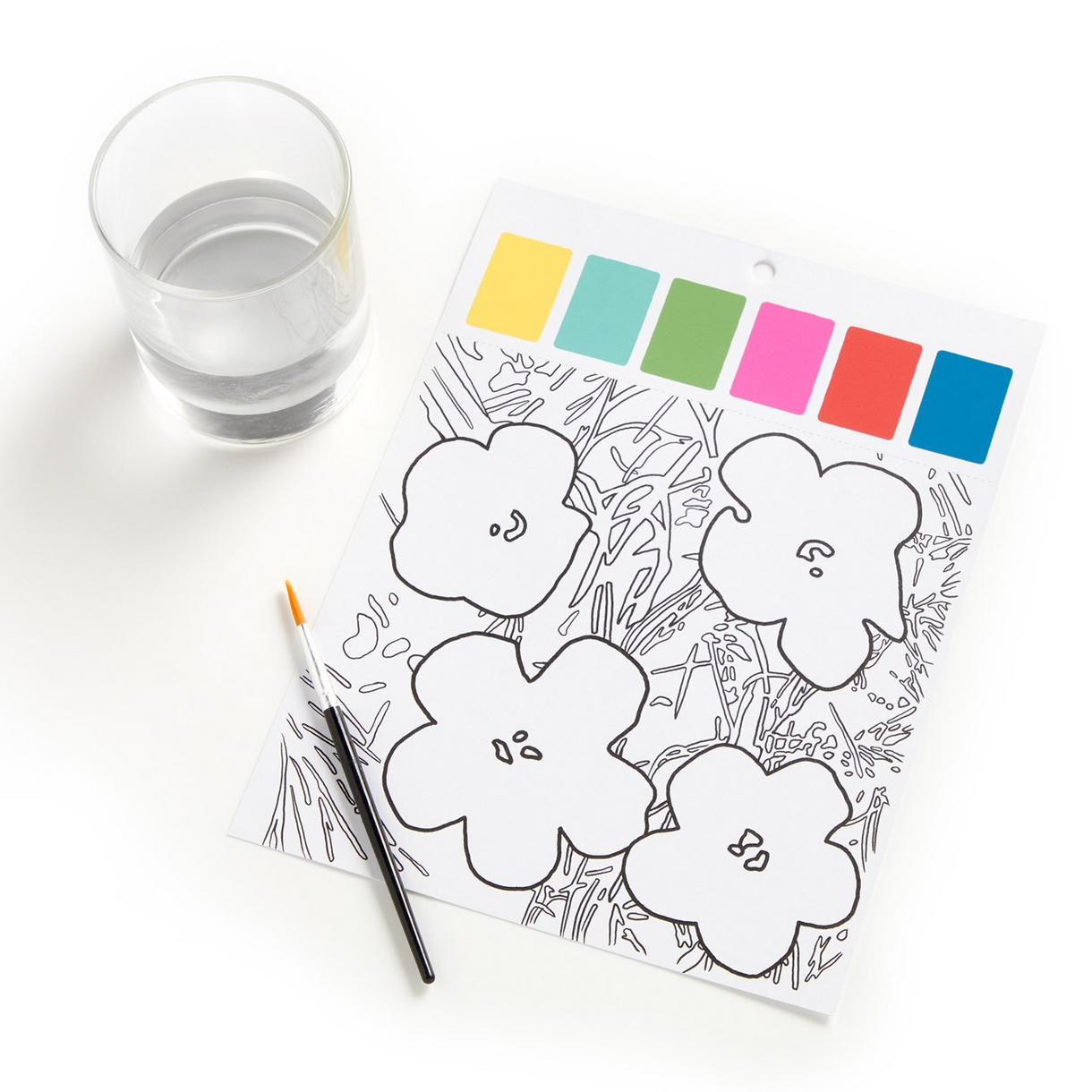 Coloring page with flowers, color swatches, and a glass of water on a white surface