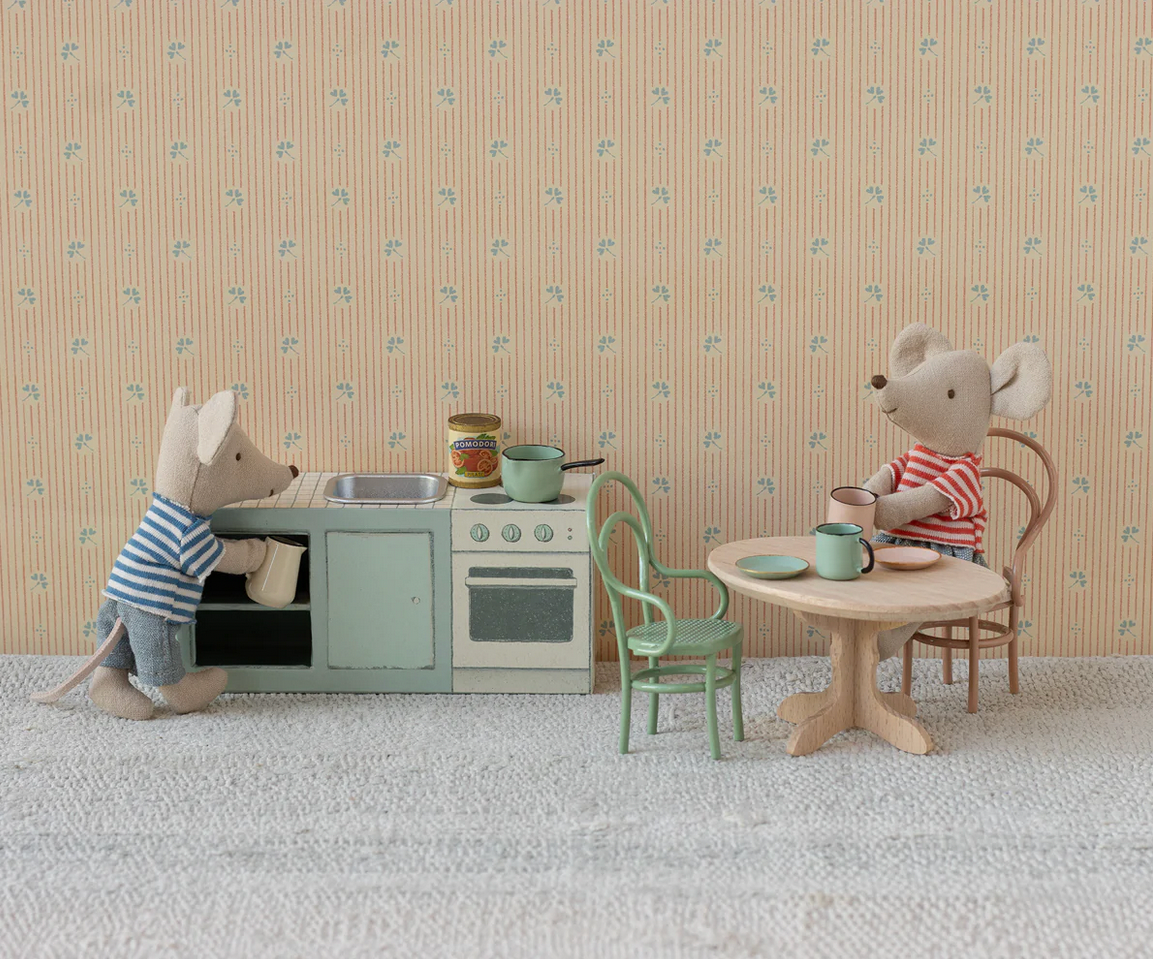 Toy kitchen set with two toy mice in a room with patterned wallpaper.