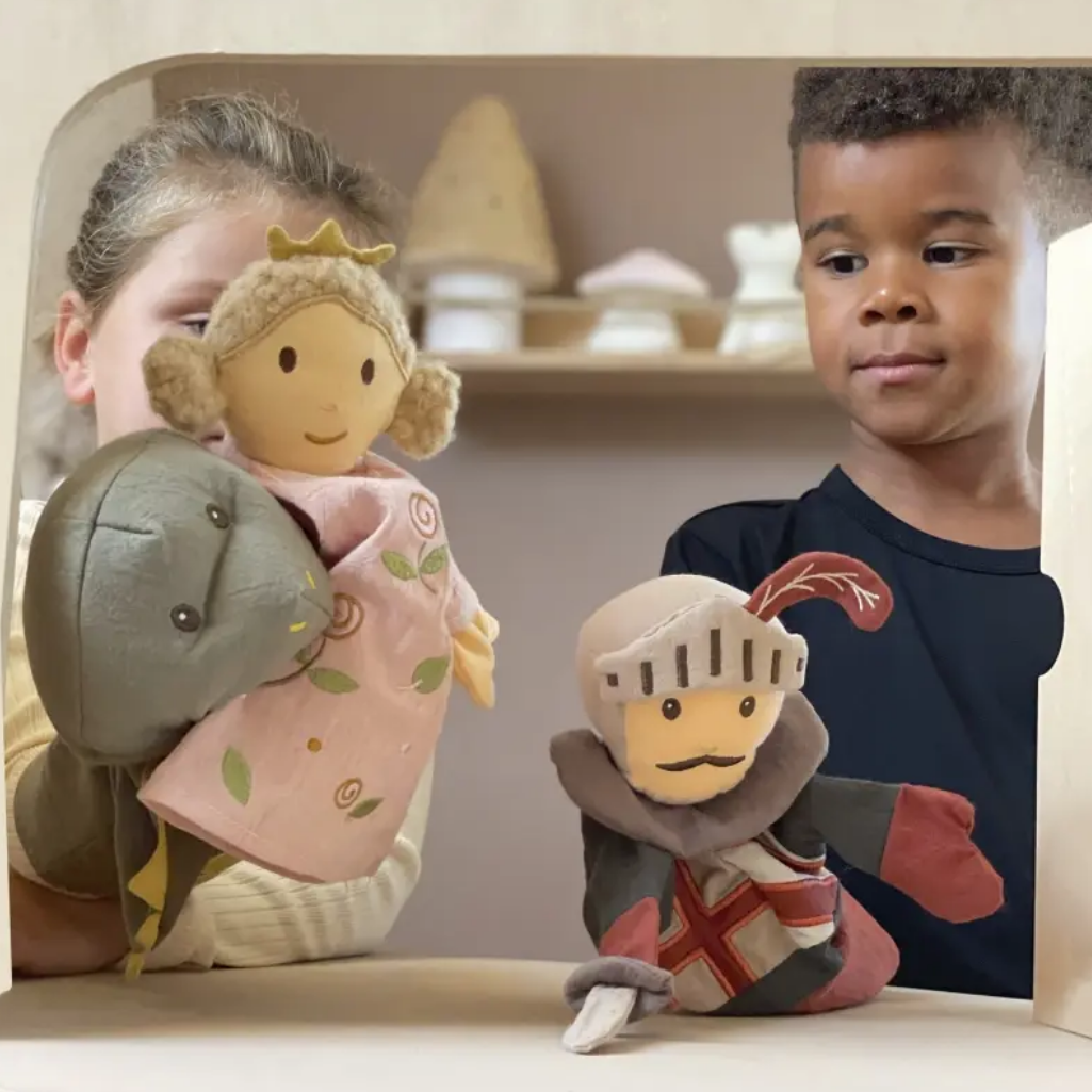 Two children with toy figures of a princess and a knight in a theater case.