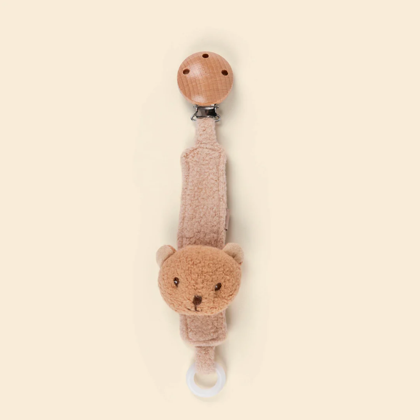 Teddy bear-shaped pacifier clip on a beige background