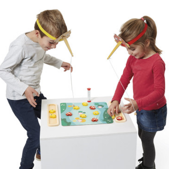Two children playing with a fishing game on a white stand.