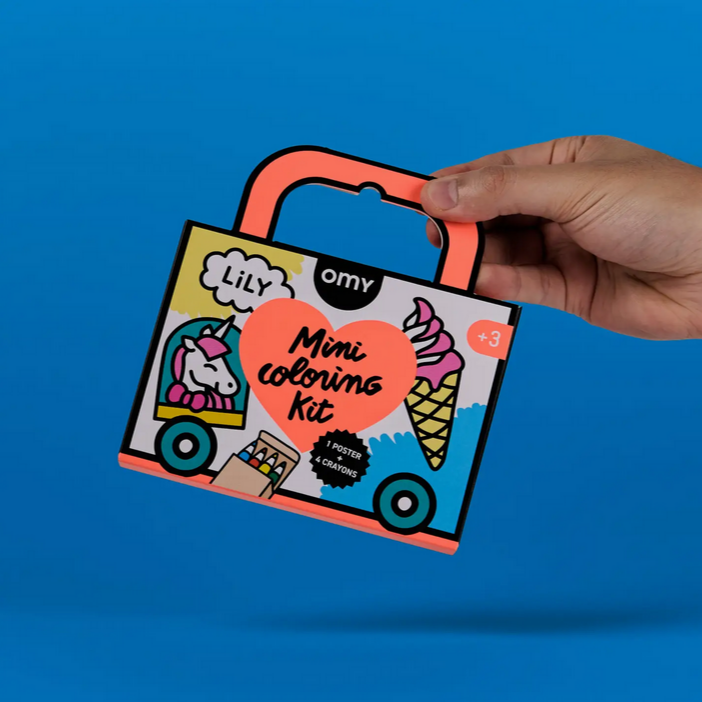 Hand holding a mini coloring kit against a blue background
