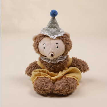 Stuffed hedhehog wearing a party hat on a beige background