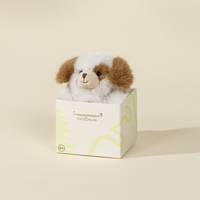 Stuffed dog toy in a white box with a brand logo on a beige background