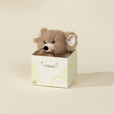 Small brown mouse in a white box with a brand logo on a beige background