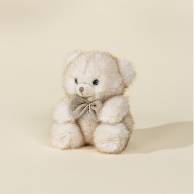White teddy bear with a bow tie on a beige background