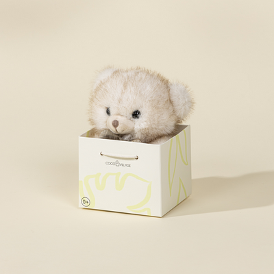 Small fluffy toy in a decorative box on a beige background