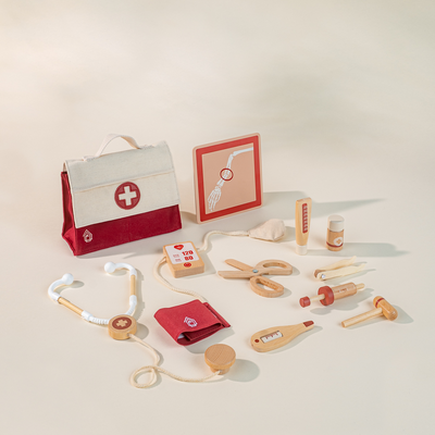 Set of toy medical equipment including a stethoscope, first aid kit, and various tools on a light background