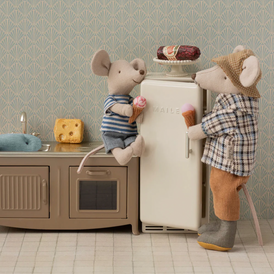 Two toy mice in a kitchen setting with a refrigerator and oven.