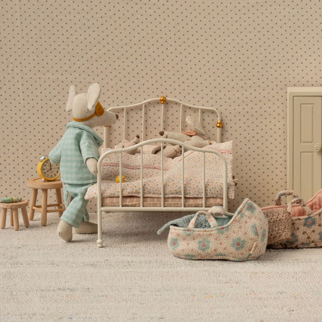 Miniature dollhouse scene with a child-like figure, bed, and furniture 