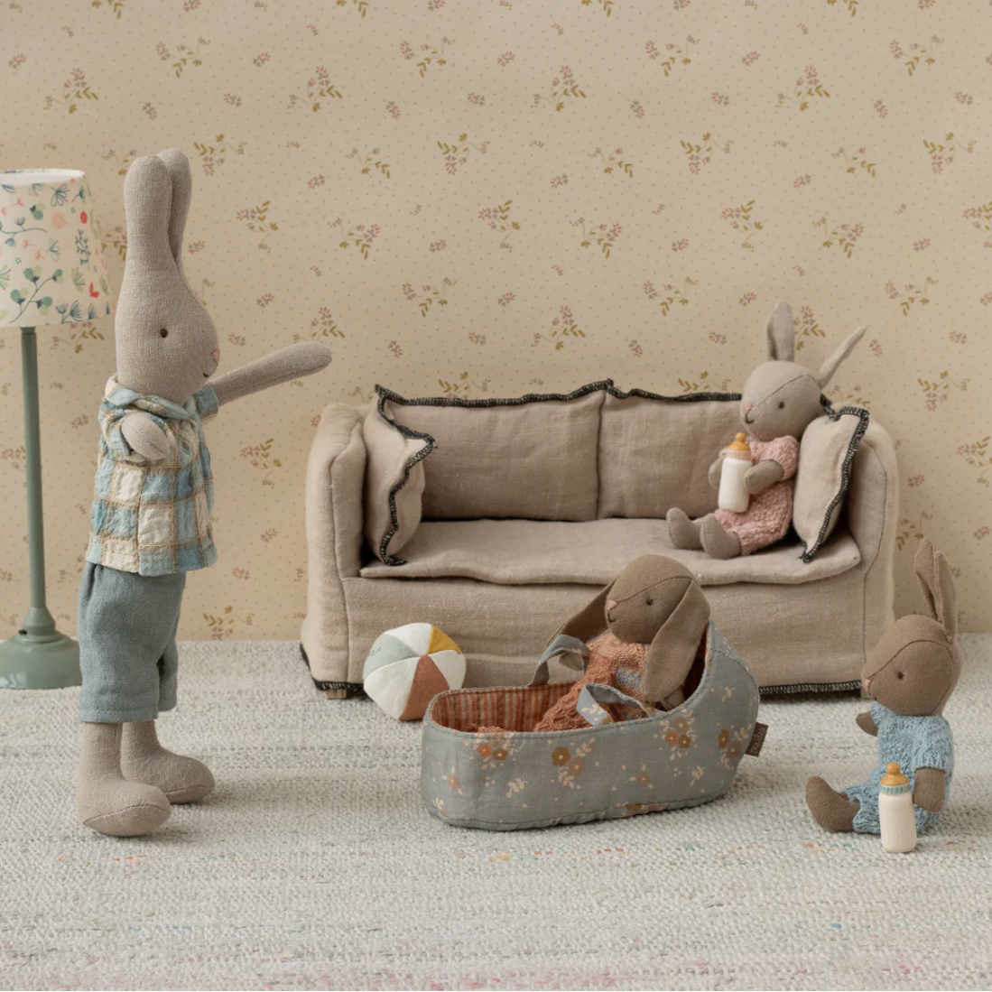 Toy rabbits in a living room setting with a sofa and lamp.