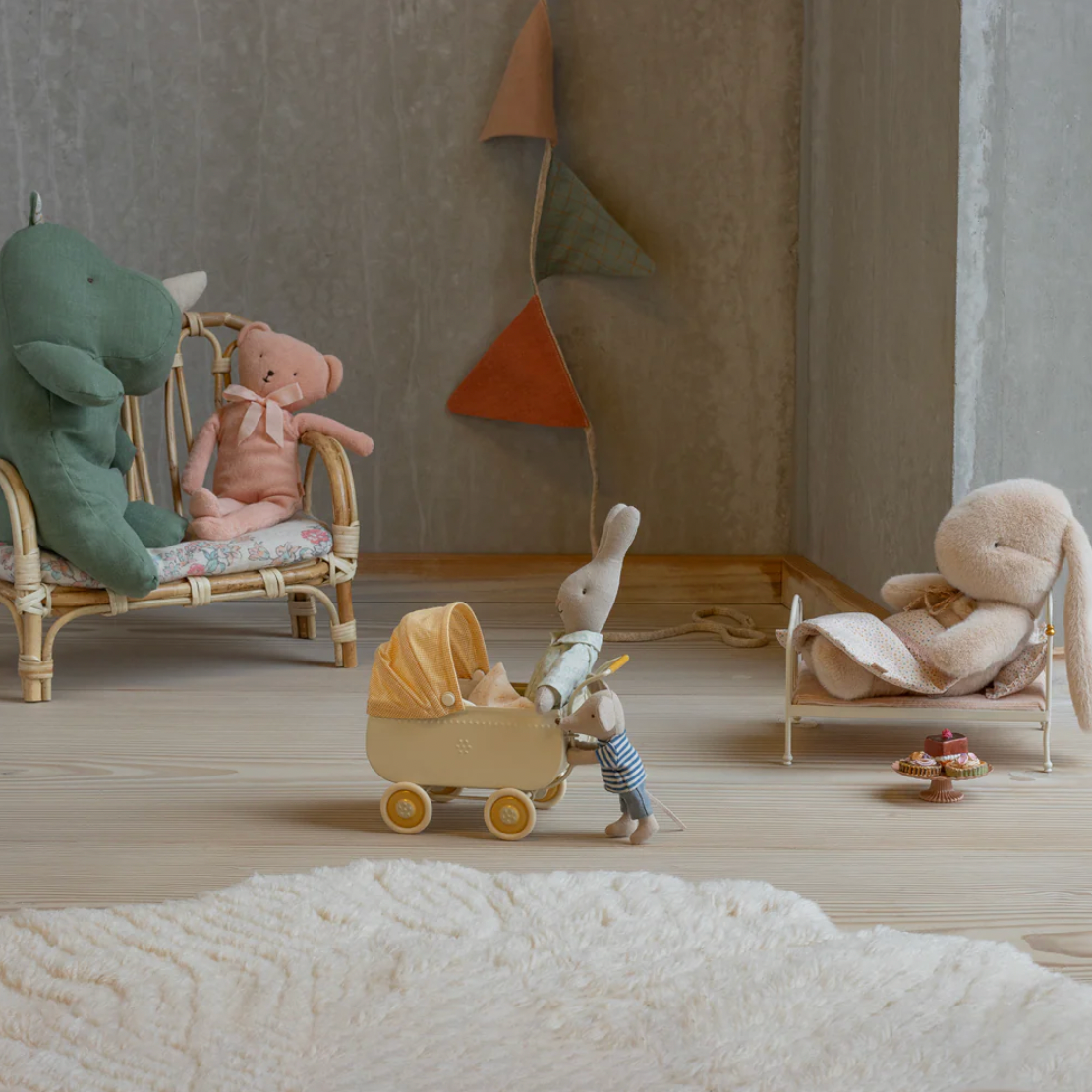 Children's room with stuffed animals on chairs and a baby buggy.