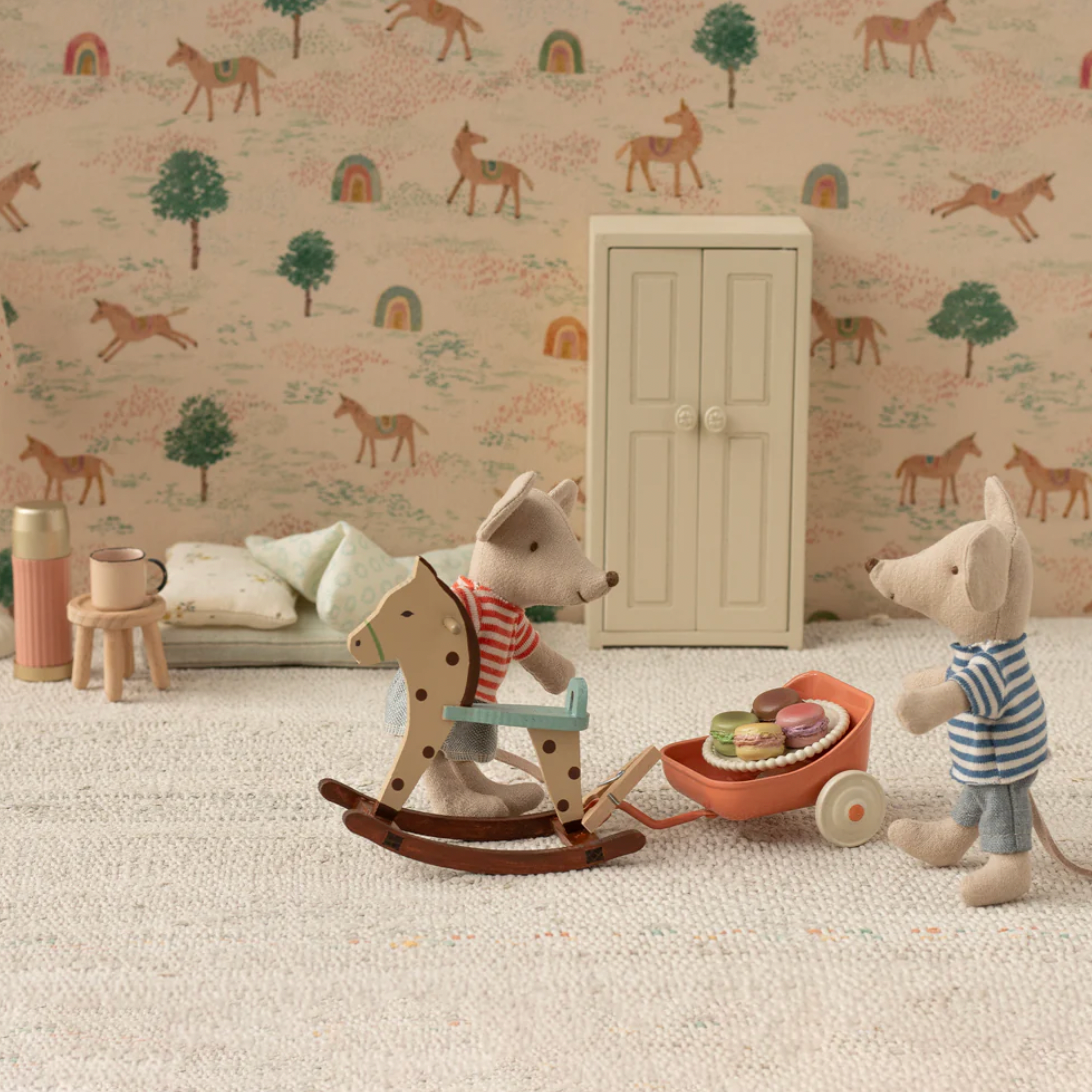 Children's room with toys, rocking horse, and wall with animal pattern
