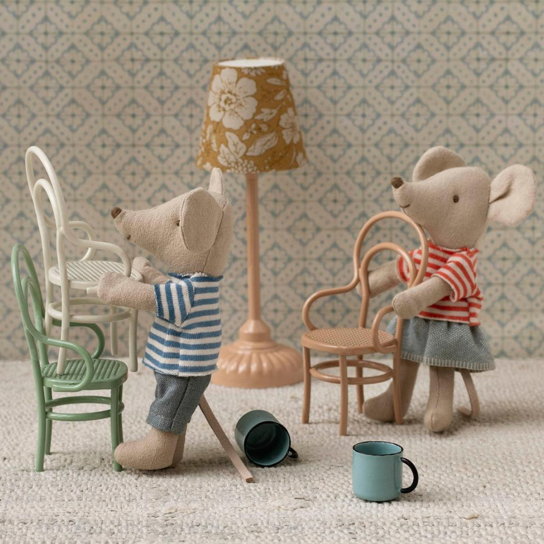 Two toy mice in a miniature room setting with furniture and decor.