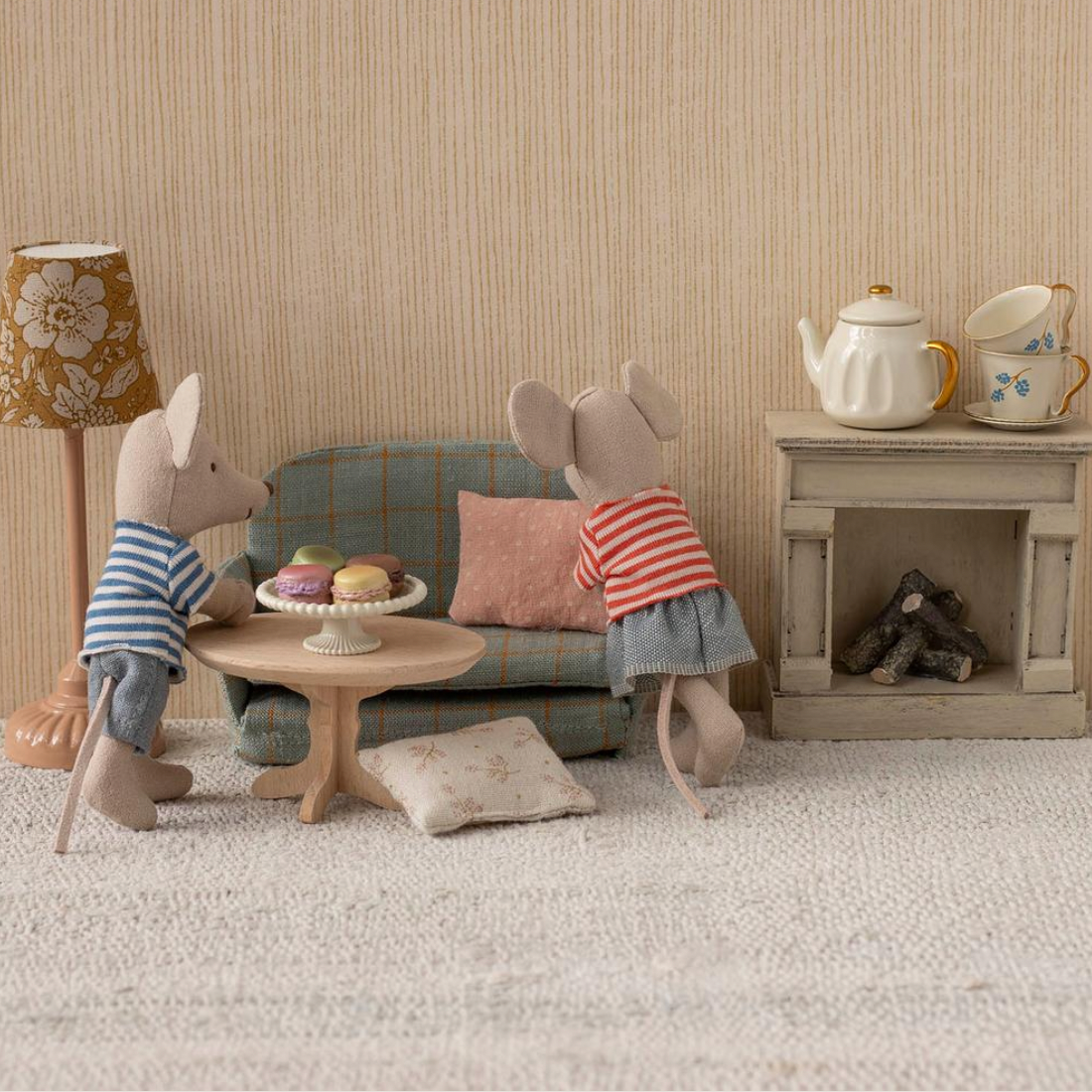 Miniature living room scene with toy mice and furniture on a website page.