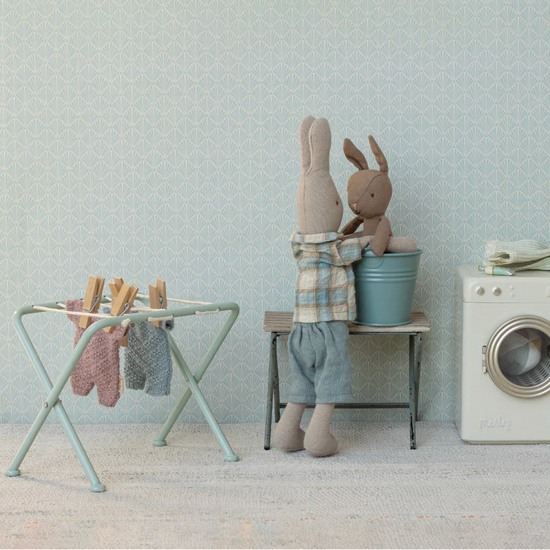 Children's room with toys, washing machine, and dryer against a light gray wall.